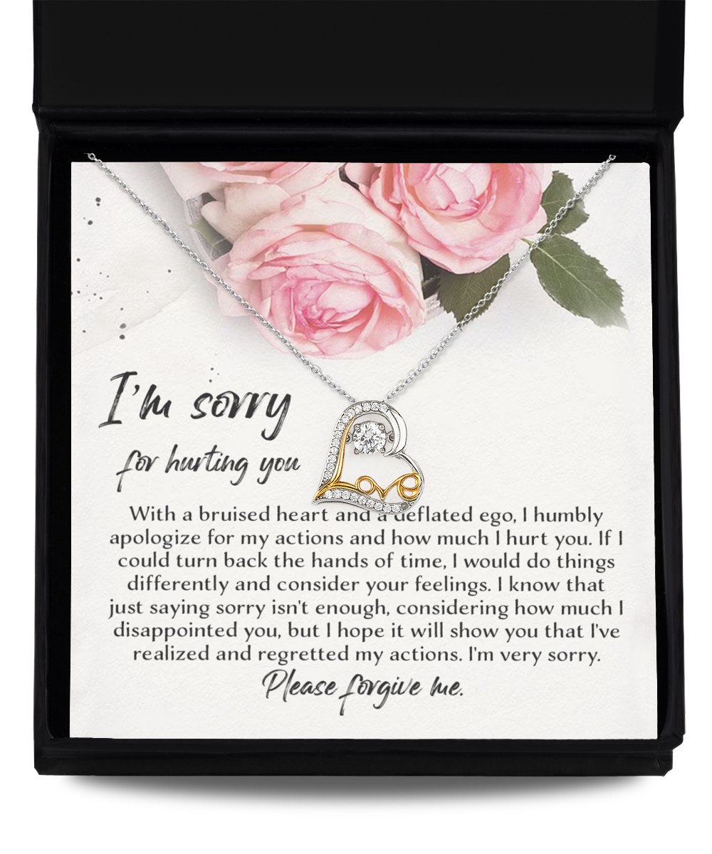 An open gift box containing the Sorry-Regreted My Actions - Love Dancing Necklace, which features a 14k gold plated heart-shaped pendant. Nestled beside the necklace is a card adorned with floral designs and a heartfelt apology note, expressing regret and seeking forgiveness for causing hurt.