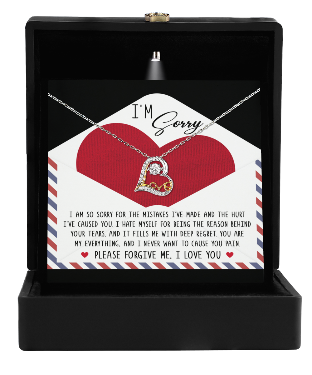 The Sorry-Behind Your Tears - Love Dancing Necklace, made of Sterling Silver and featuring a heart pendant, rests elegantly in a black box. Behind it lies a card with an apology message, expressing heartfelt regret and seeking forgiveness.