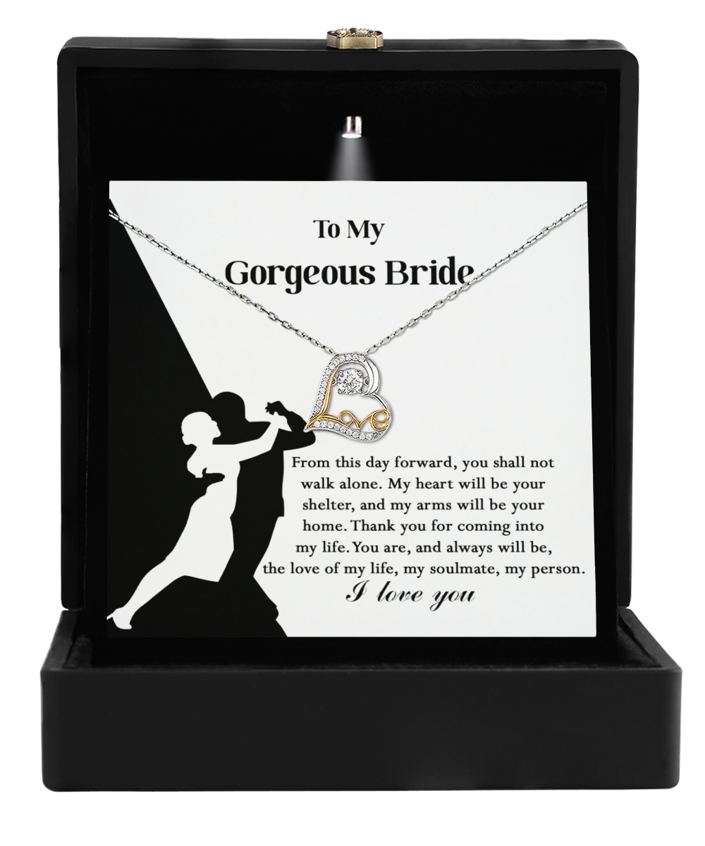 The Bride-Be Your Home - Love Dancing Necklace presents a gold heart pendant elegantly displayed on a card with a dancing couple's silhouette and is beautifully packaged in a sleek black box. This makes it the ideal bridal gift to honor love and special memories.