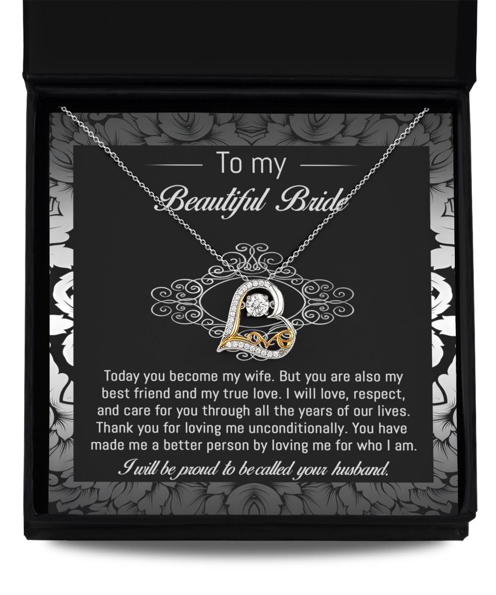 A 14k gold "To Bride-My True Love - Love Dancing Necklace" with a heart-shaped pendant rests in a black and white box. The inside of the box lid has a message addressed to a bride from her husband, expressing love and commitment.