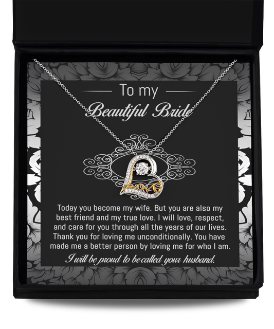 A 14k gold "To Bride-My True Love - Love Dancing Necklace" with a heart-shaped pendant rests in a black and white box. The inside of the box lid has a message addressed to a bride from her husband, expressing love and commitment.