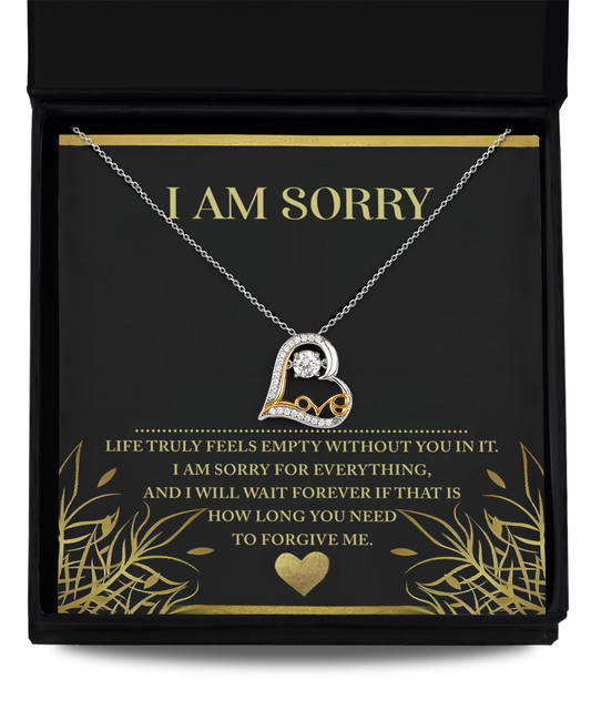 The Sorry-Without You - Love Dancing Necklace, a silver heart-shaped piece featuring an embedded 'A', is elegantly displayed in an open black box. Inside the box, a card reads "I AM SORRY" with an apologetic message below. This charming piece seamlessly combines elegance and sentiment, making it perfect for expressing heartfelt remorse.