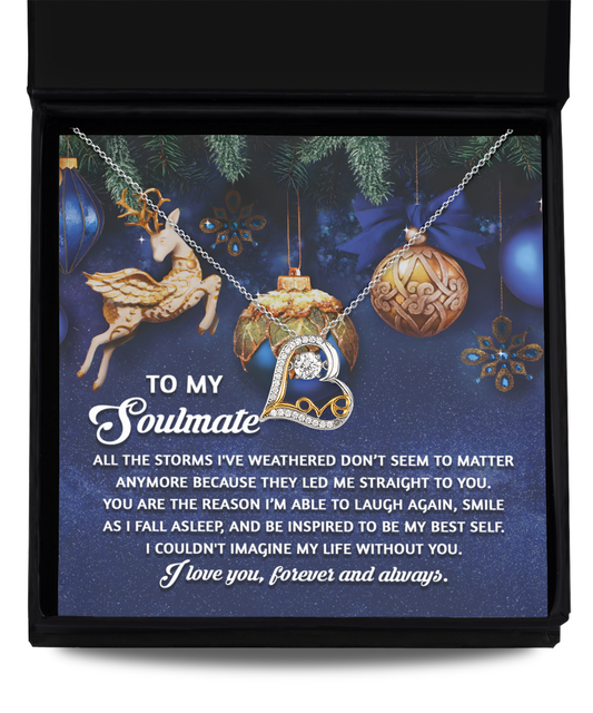 The Soulmate-Straight To You - Love Dancing Necklace, made from sterling silver, showcases a heart pendant inside a gift box and includes a heartfelt message for your soulmate. Displayed on a festive background adorned with ornaments and a reindeer, this necklace is the perfect symbol of love.