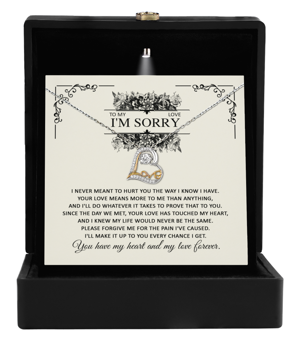 A golden heart-shaped "Sorry-Every Chance - Love Dancing Necklace" adorned with small diamonds is displayed inside an open black jewelry box. Behind the 14k gold necklace, a heartfelt apology note is visible, expressing deep remorse and a promise of everlasting love.