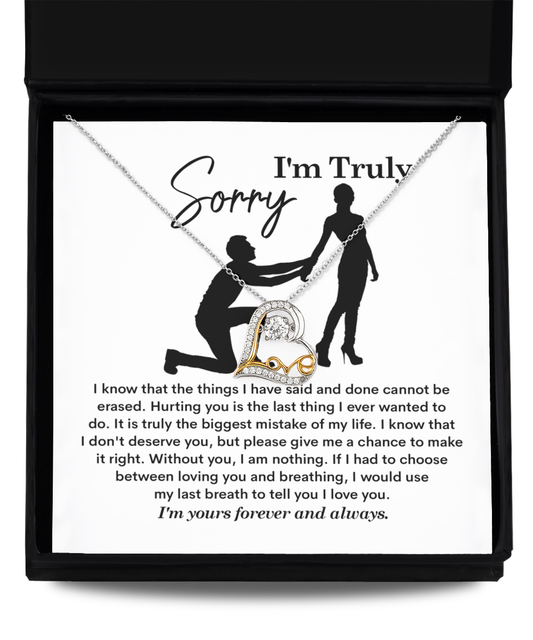 A Sorry-My Last Breath - Love Dancing Necklace, featuring a heart-shaped pendant crafted from .925 Sterling Silver, is placed on top of a note with the heading "I'm Truly Sorry" and an illustration of a person on one knee offering their hand to another person.