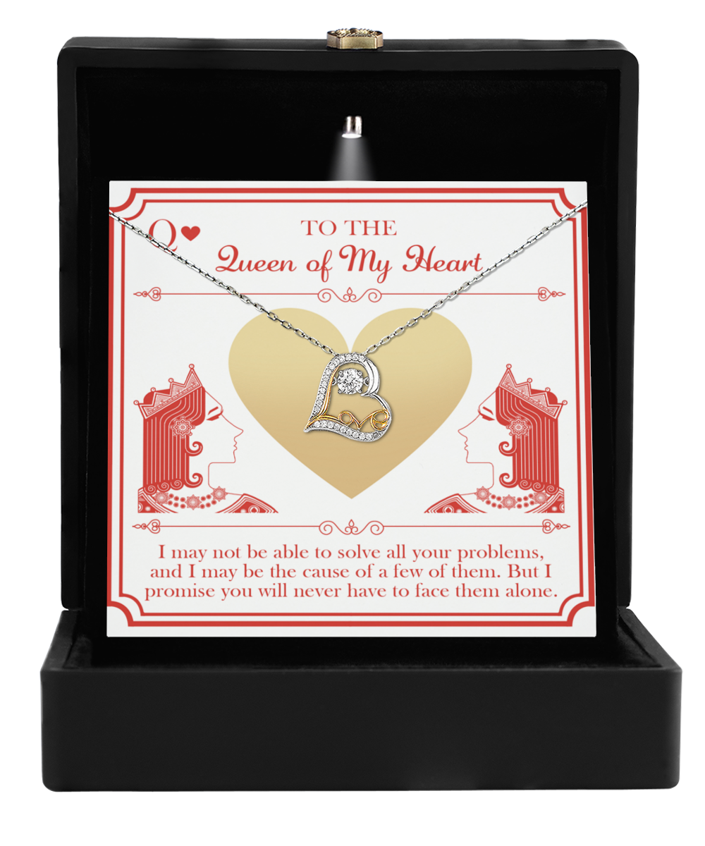 A heart-shaped, sterling silver necklace with a sparkling pendant, displayed in an open black box with a card behind it reads "To the Queen of My Heart" and features illustrations of queens and a heartfelt message beneath. The product is called the "To Wife-The Queen - Love Dancing Necklace.