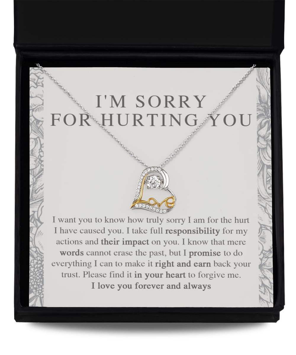 The Sorry-Do Everything - Love Dancing Necklace, a heart-shaped 14k gold piece, is showcased in a black box. Accompanying the necklace is an apology note featuring a heartfelt message of regret and a promise to make amends. The note is gray with floral patterns adorning the borders.