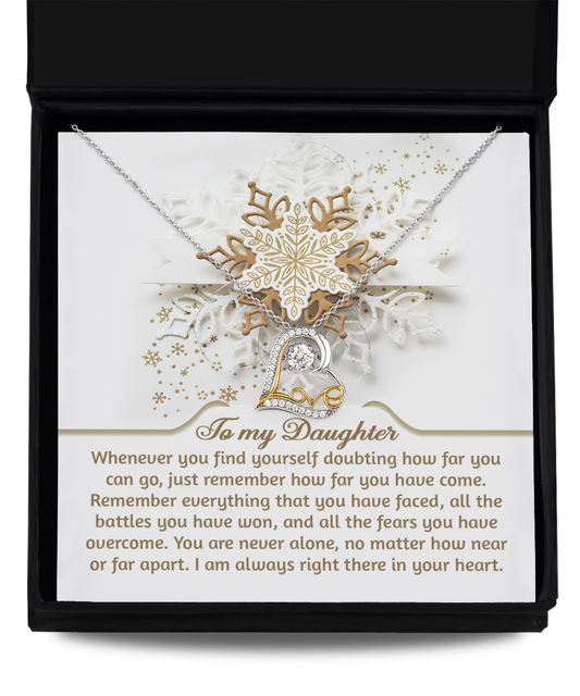 The "Daughter-You Can Go- Love Dancing Necklace" comes beautifully packaged in a gift box with a heartfelt note starting with "To my Daughter," providing encouragement and assuring, "I am always right there in your heart." This necklace, crafted from sterling silver, boasts intricate designs and a central heart pendant, symbolizing love and connection.