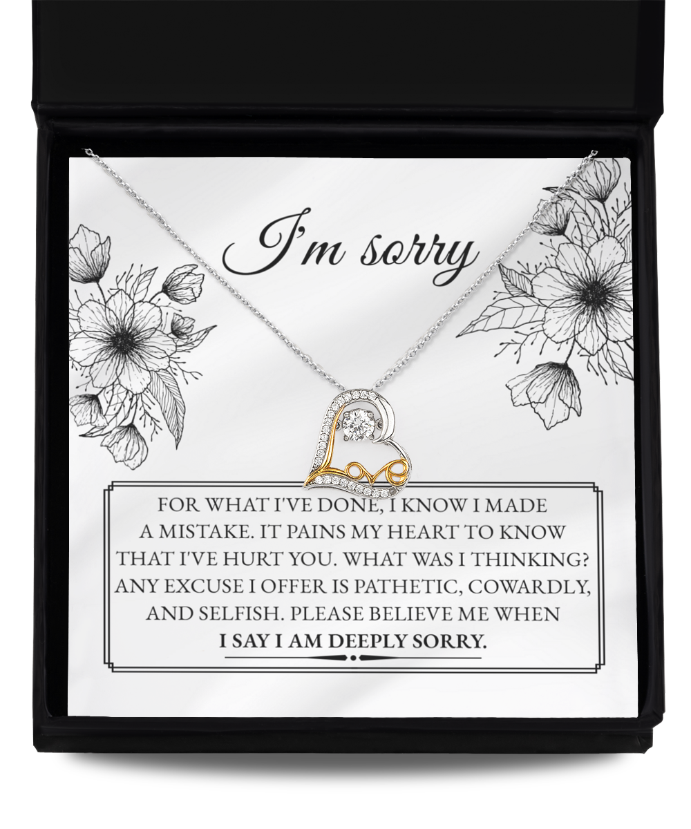 A 14k gold necklace with an intertwined heart design from the "Sorry-Made A Mistake - Love Dancing Necklace" collection is presented in a box. The text inside conveys an apology for causing pain, expressed with deep regret and a heartfelt plea to believe in the sincerity of the apology.