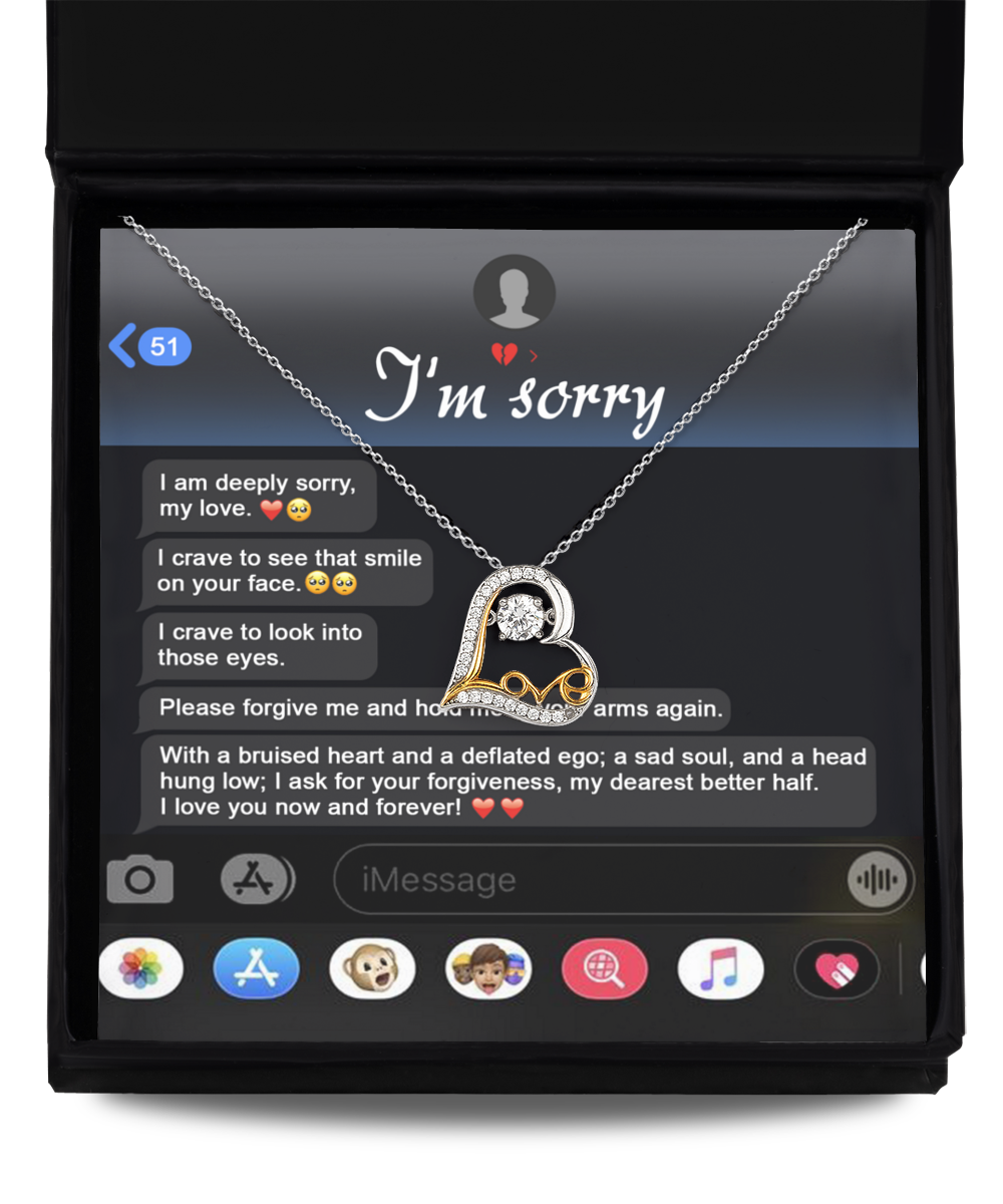 A Sorry-Rebuild Our Connection - Love Dancing Necklace, featuring a heart-shaped pendant crafted from silver and 14k gold, is placed inside a jewelry box. The background displays a message on a phone screen saying "I'm sorry" and a heartfelt apology.