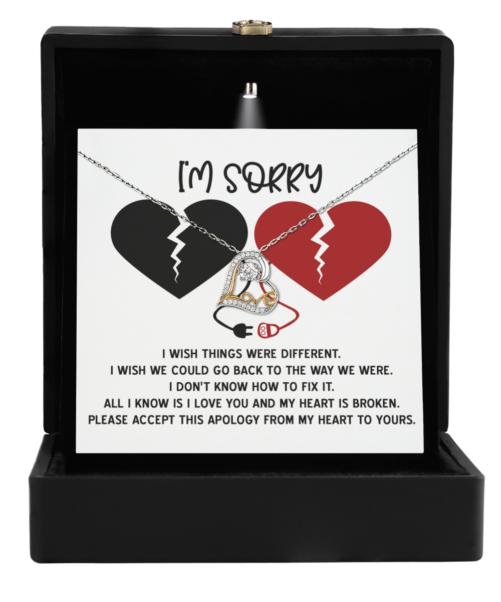 An open jewelry box unveils the dazzling Sorry-Heart Is Broken - Love Dancing Necklace with a heart pendant, elegantly displayed on a card featuring broken heart images and an apology message.