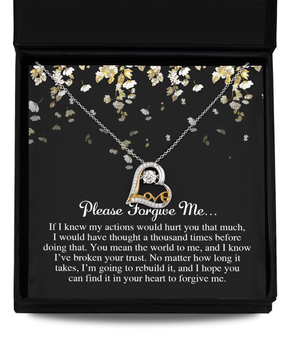 A heart-shaped necklace featuring a clear gem is placed in a black box. Named the Sorry-Broken Your Trust - Love Dancing Necklace, it is crafted from sterling silver. The lid of the box includes an apology message that begins with "Please Forgive Me..." and concludes with a note about rebuilding trust, adorned with floral designs.