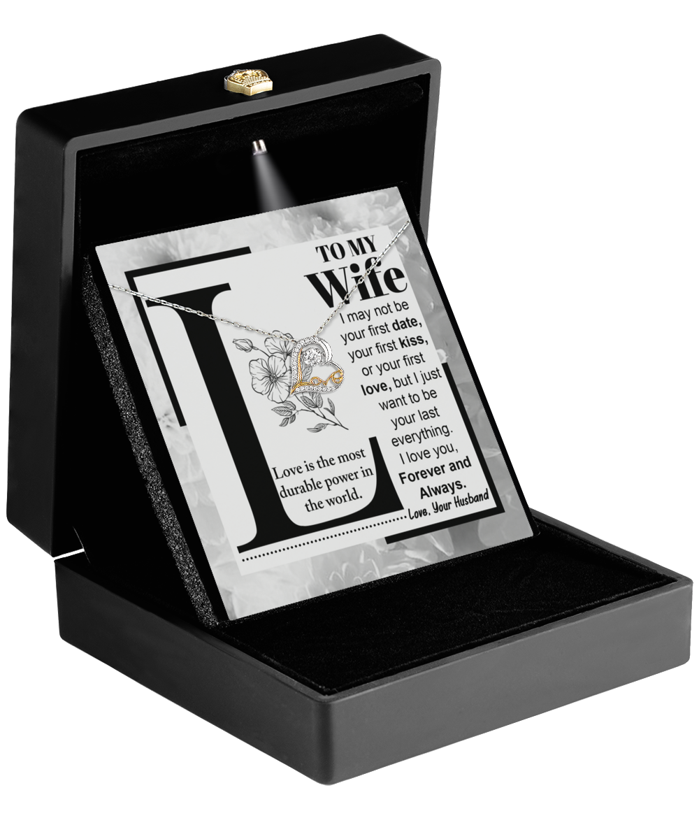 Open black box featuring the "To Wife, Love Is - Love Dancing Necklace," showcasing a decorative plaque with a heartfelt message to a wife. The floral design is softly illuminated, and an elegantly dangling heart-shaped pendant adds charm and sentimentality.