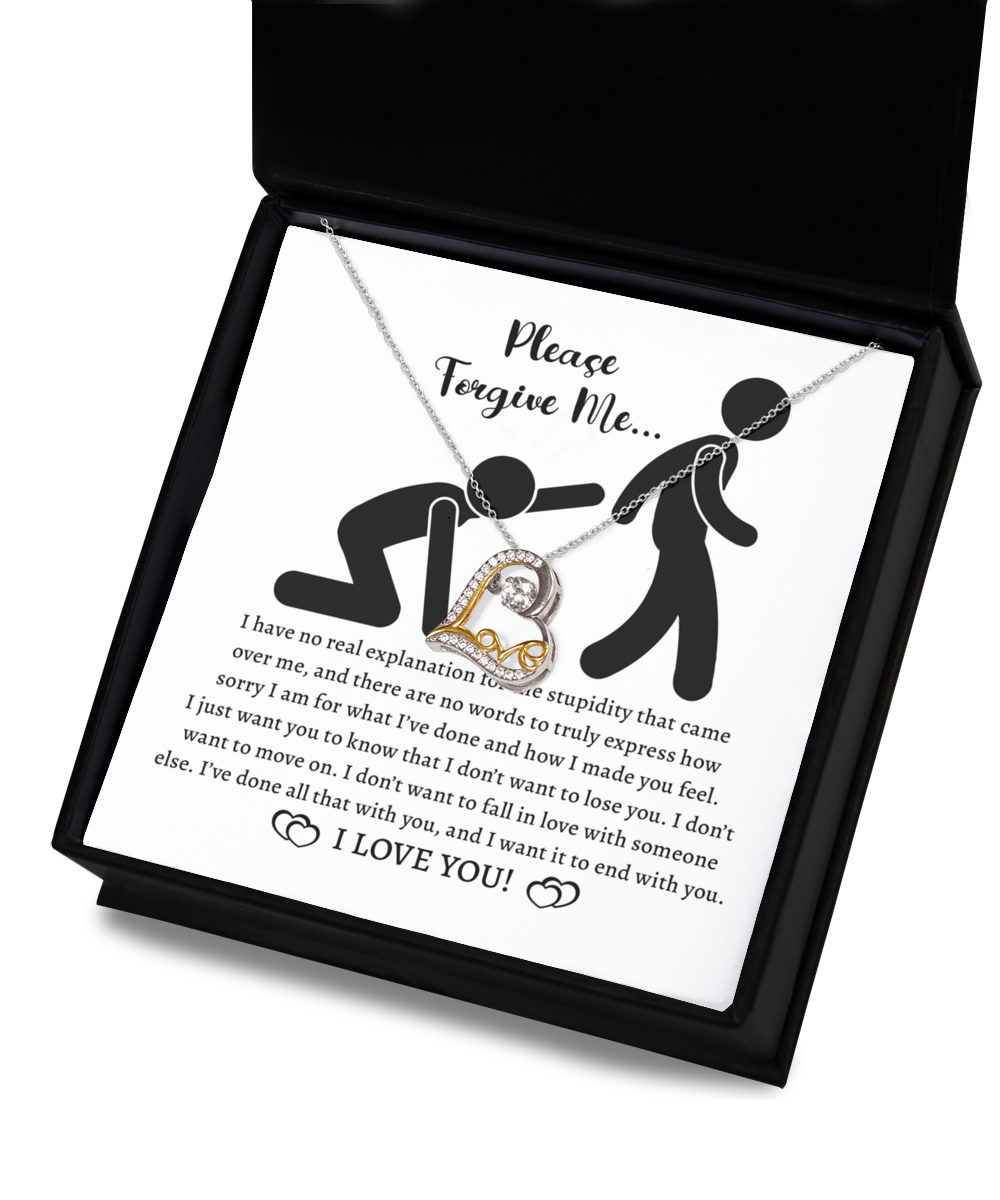 The Sorry-Made You Feel - Love Dancing Necklace, a stunning 14k gold piece with a heart pendant, rests elegantly on top of a card in an open box. The card features a heartfelt apology message accompanied by an illustration of one person kneeling and chained to another.