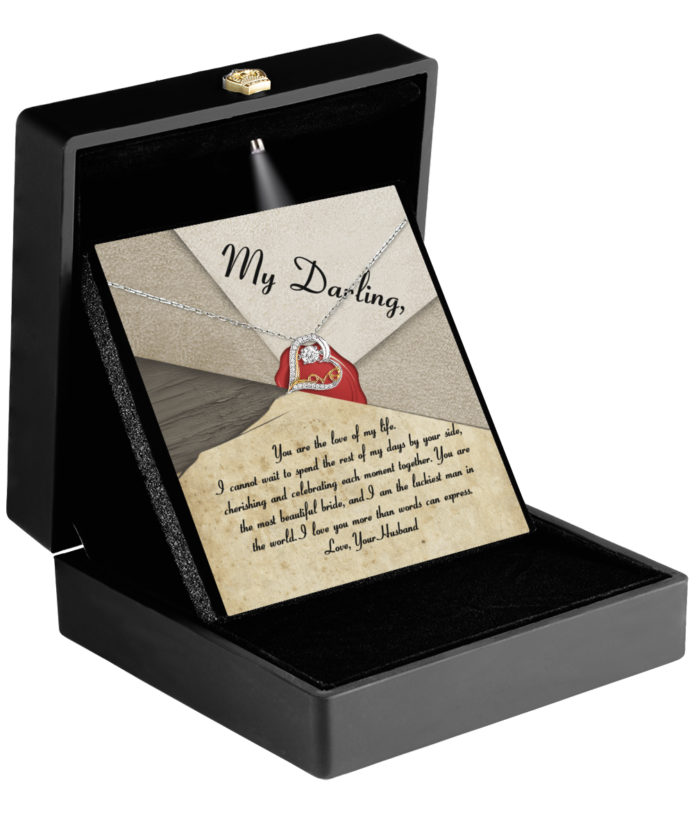 In an open black jewelry box, the breathtaking Bride-Each Moment Together - Love Dancing Necklace with a cubic zirconia pendant is elegantly set in 14k gold on a velvet cushion. Accompanying it is a love note titled “My Darling,” adorned with an illustration of an envelope and a red wax seal, making it the perfect unforgettable gift for a bride.