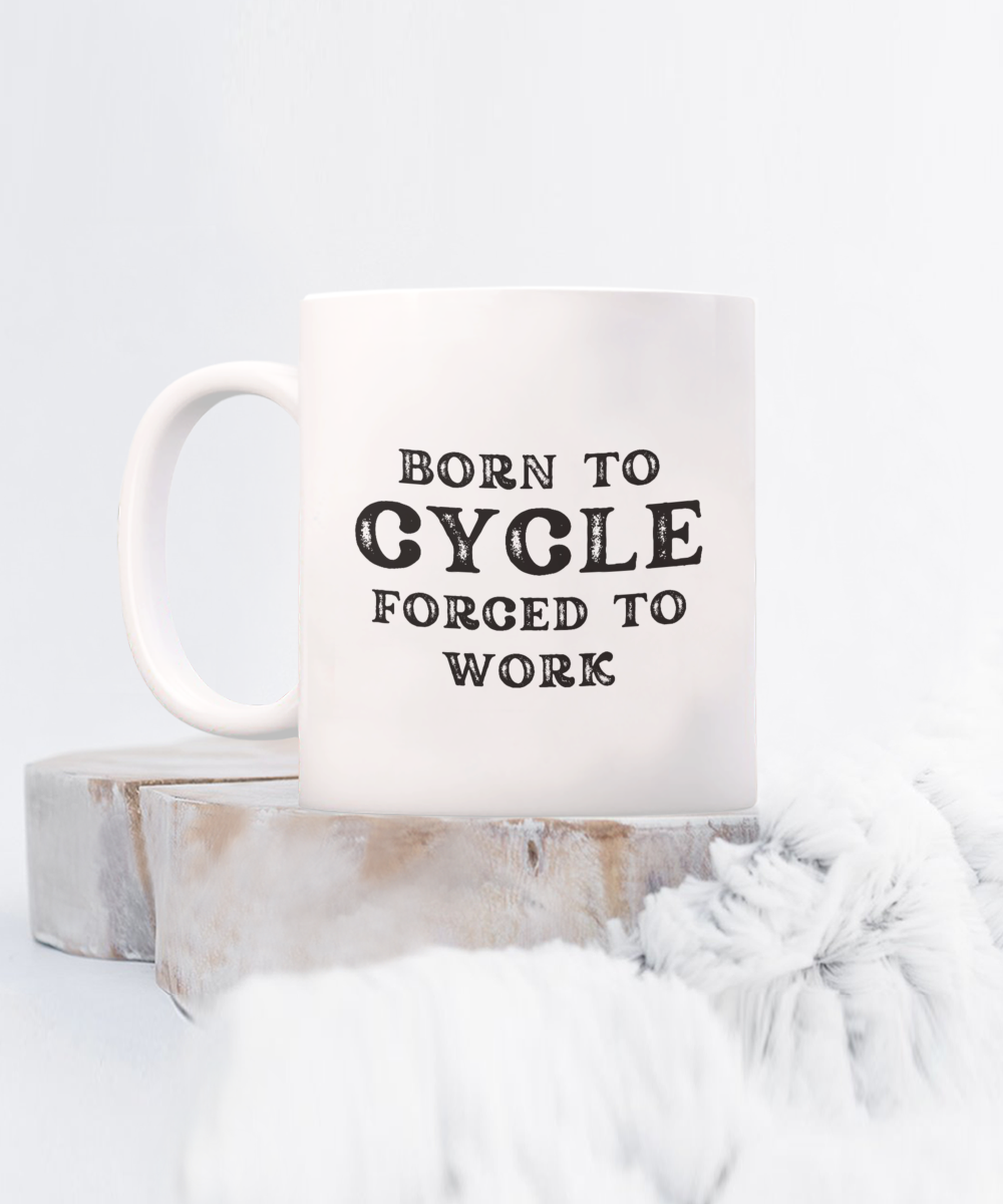 Get the "Born to Cycle, Forced to Work" Coffee Mug featuring a white base and soft gray background. This exclusive design is printed and shipped from the USA. Available for a limited time only!.