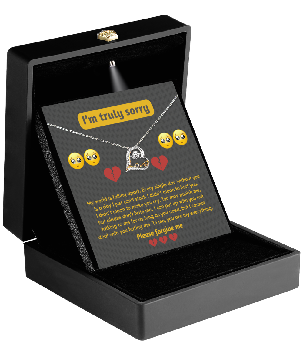 A black box containing the Sorry-Make You Cry - Love Dancing Necklace with a heart-shaped pendant. Crafted from 14k gold, it includes a note with an apology message, emojis of sad faces and hearts, and the text "I'm truly sorry" at the top.