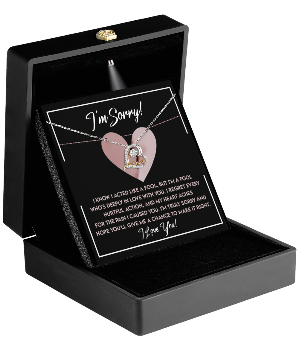 A beautifully packaged Sorry-Deeply In Love - Love Dancing Necklace, crafted in 14k gold and featuring a circular pendant, comes in a sleek black gift box. Inside, you'll find a heartfelt apology message printed on a card with a charming pink heart background.