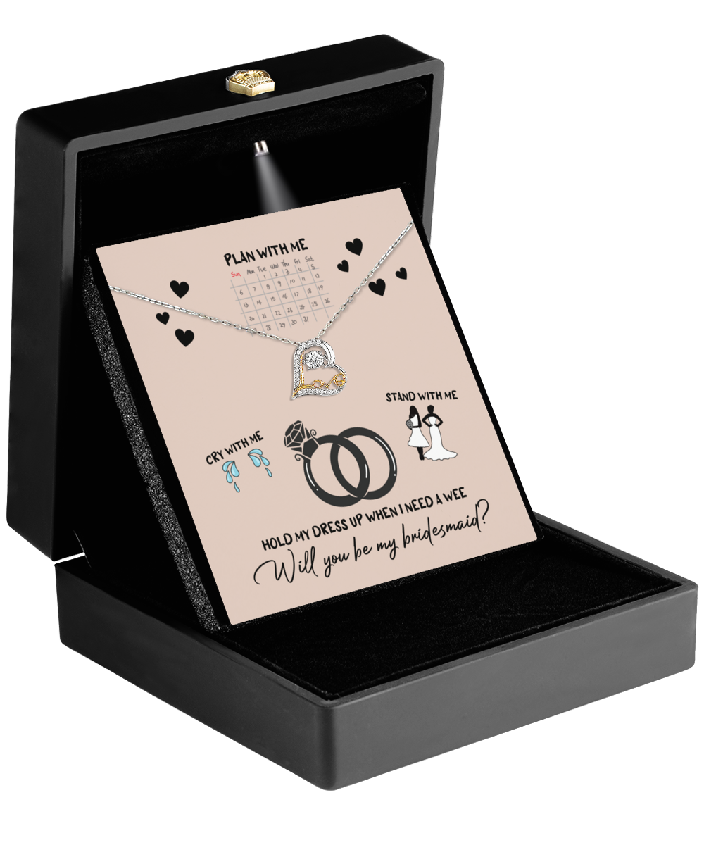 The Bridesmaid-Will You Be 2 - Love Dancing Necklace is elegantly presented in a black box, accompanied by a card adorned with wedding icons and the message: "Will you be my bridesmaid?" This stylish and sentimental gift makes for the perfect keepsake on your special day.