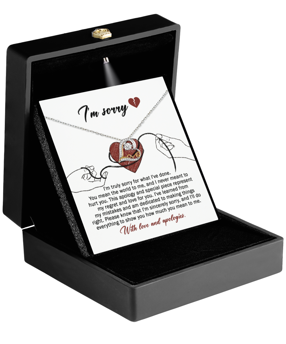 The Sorry-Mean The World Love Dancing Necklace, crafted in 14k gold, is presented in a black box and comes with an "I'm sorry" card adorned with a heart design.