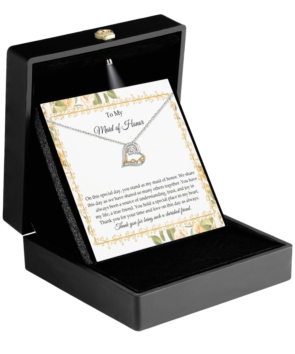 The To Maid of Honor-Share This Day - Love Dancing Necklace, featuring a heart pendant, is elegantly presented in a black box. Accompanied by a card with a floral border that reads, "To My Maid of Honor," it beautifully conveys friendship and gratitude. This 14k gold piece is the perfect token of appreciation for someone truly special.