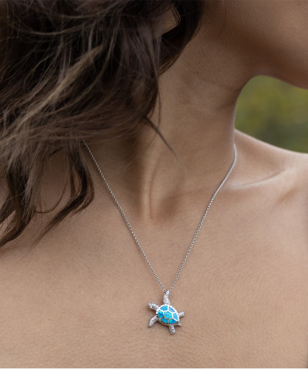 A close-up photograph of a person wearing a Gearbubble Opal Turtle Necklace, a symbol of love.