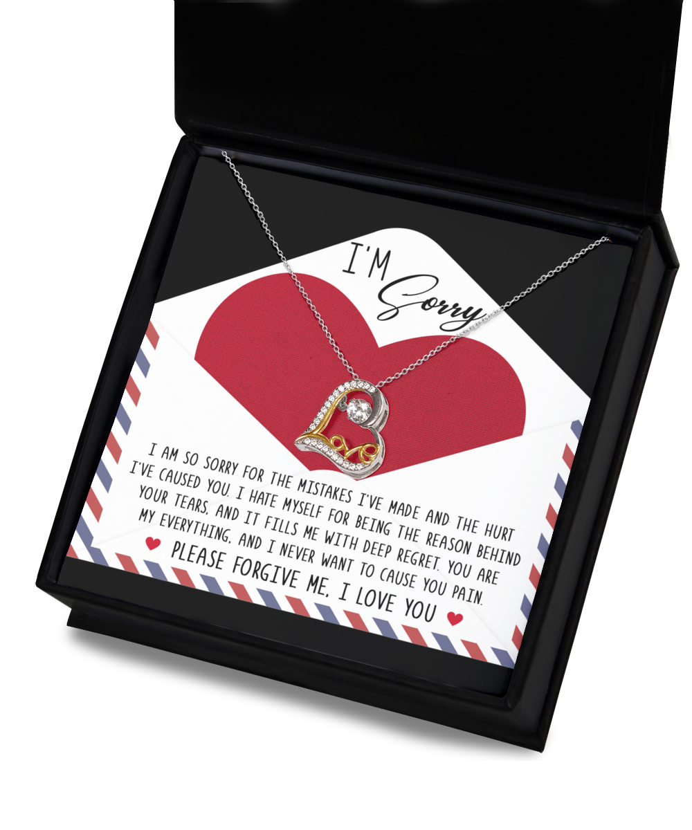 The "Sorry-Behind Your Tears - Love Dancing Necklace," made of sterling silver hypoallergenic material, comes elegantly displayed in an open black gift box. The accompanying card features an apology message and a large red heart, ensuring both elegance and comfort for sensitive skin.