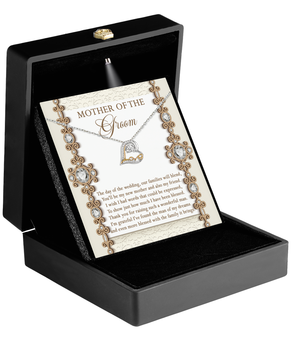 A 14k gold necklace with a heart pendant is elegantly showcased in a black box and comes with a floral-decorated card titled "Mom Of Groom-New Mother." This Love Dancing Necklace beautifully encapsulates the essence of love and joy on such a special day.