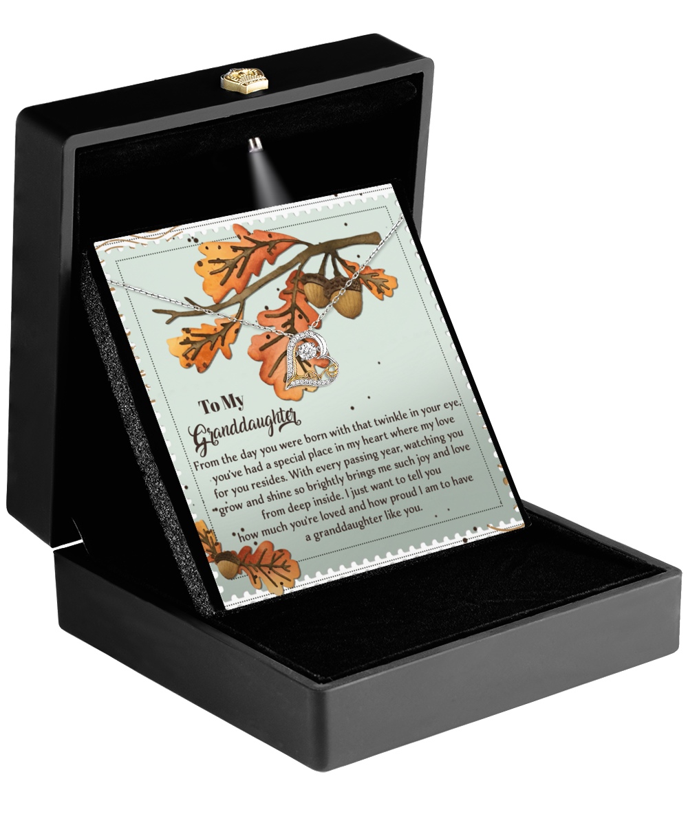 A jewelry gift box opens to reveal the Granddaughter-From Deep Inside - Love Dancing Necklace crafted from sterling silver, along with a card featuring an autumn leaf design and a heartfelt message for a granddaughter.