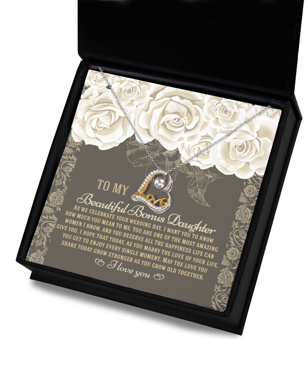 The "To Bonus Daughter - Grow Old Together - Love Dancing Necklace" is a heart-shaped pendant crafted from .925 Sterling Silver, beautifully presented in a box alongside a card. The card features an emotional message to a daughter on her wedding day, adorned with floral illustrations.