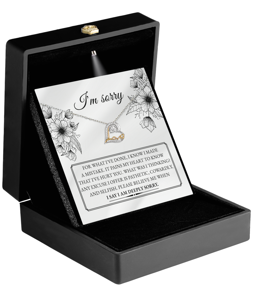 A Sorry-Made A Mistake - Love Dancing Necklace, artfully crafted in 14k gold, is nestled in a black jewelry box with an apology card saying, "I'm sorry" and a heartfelt message.