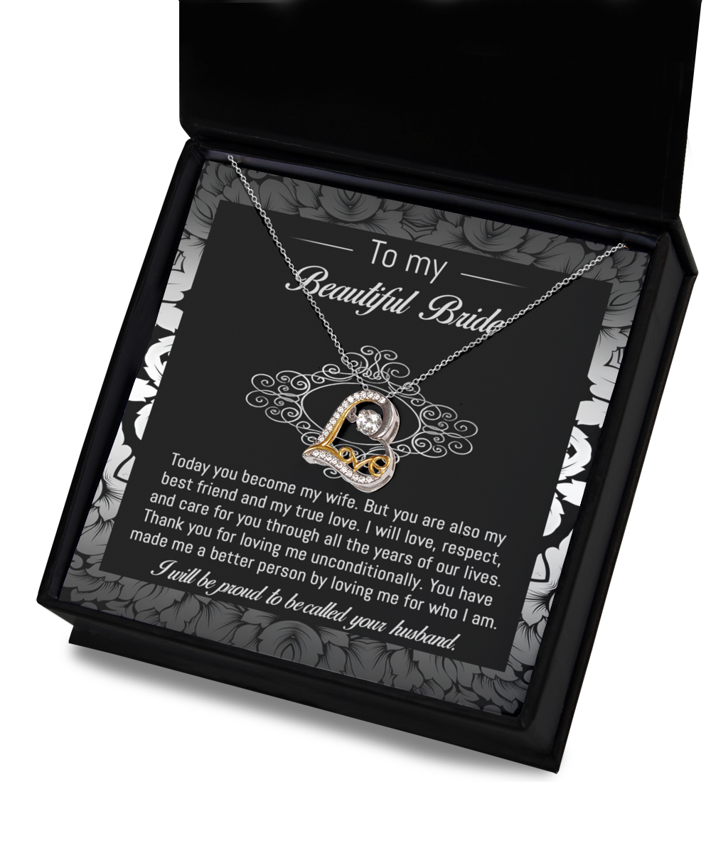 A 14k gold "To Bride-My True Love - Love Dancing Necklace" with a heart-shaped pendant rests in a black and white box. The inside of the box lid has a message addressed to a bride from her husband, expressing love and commitment.