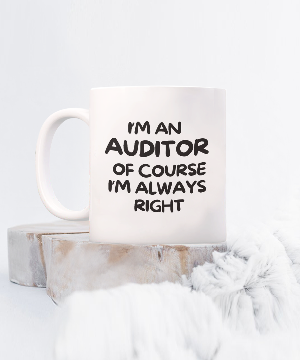 The "I'm An Auditor Of Course I'm Always Right" white mug rests on wooden coasters with a fluffy backdrop. This unique piece, not sold in stores, is available for a Limited Time Only.