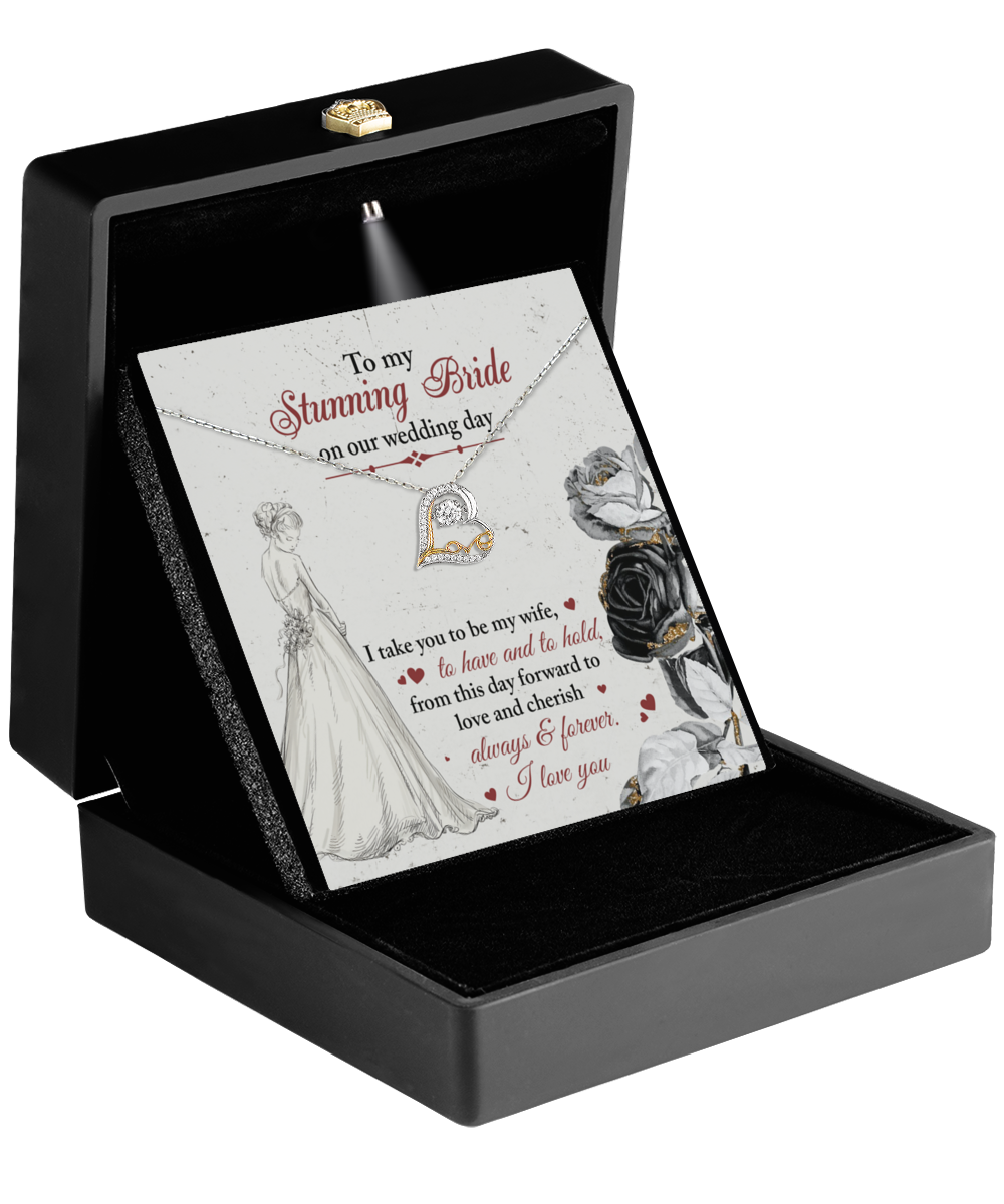 A jewelry box in black, with its lid open, displays the Bride-Be My Wife - Love Dancing Necklace alongside a heartfelt engraved message for the bride, accented with elegant rose illustrations.