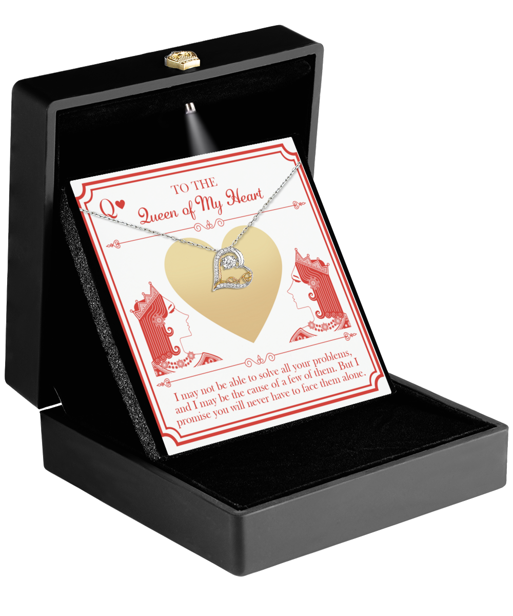 A black jewelry box containing the "To Wife-The Queen - Love Dancing Necklace," a 14k gold heart-shaped pendant with a diamond, displayed on a card adorned with red and white designs featuring two queen illustrations. The card reads, "To the Queen of My Heart" along with an affectionate message below.