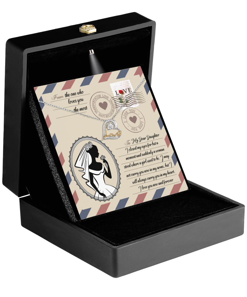 A black jewelry box featuring a card with a silhouette of a bride and an affectionate message about love offers the perfect gift: the Daughter Wedding-In My Arms - Love Dancing Necklace, adorned with two elegantly intertwined heart-shaped pendants.