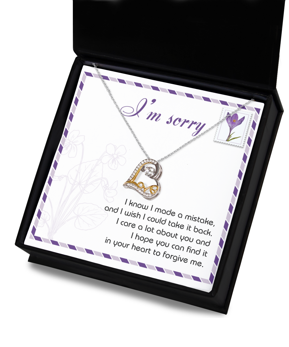 The Sorry-Take It Back - Love Dancing Necklace, a sterling silver and 14k gold heart-shaped piece, is displayed with a card that says "I'm sorry" above an apology message in a decorative box.