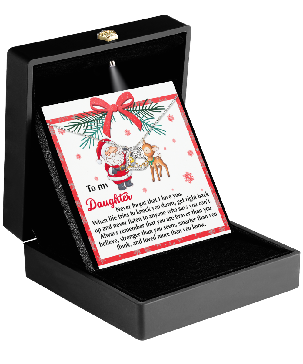 An open card displaying a heartfelt message to a daughter is nestled in a box. Ornate with Santa and reindeer decorations, this card includes the exquisite Daughter-Get Back Up - Love Dancing Necklace crafted in 14k Gold. Wrapped in a red ribbon, it perfectly complements the holiday-themed design.