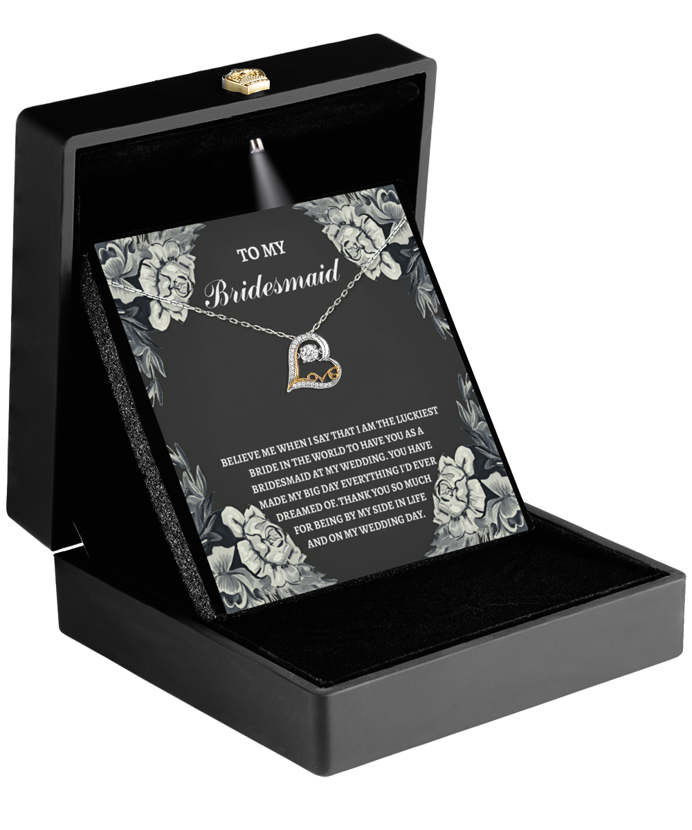 A To Bridesmaid-The Luckiest Bride - Love Dancing Necklace, elegantly crafted in 14k gold, lies displayed in a black box adorned with floral graphics. The message reads, "To My Bridesmaid," capturing the essence of gratitude and friendship.