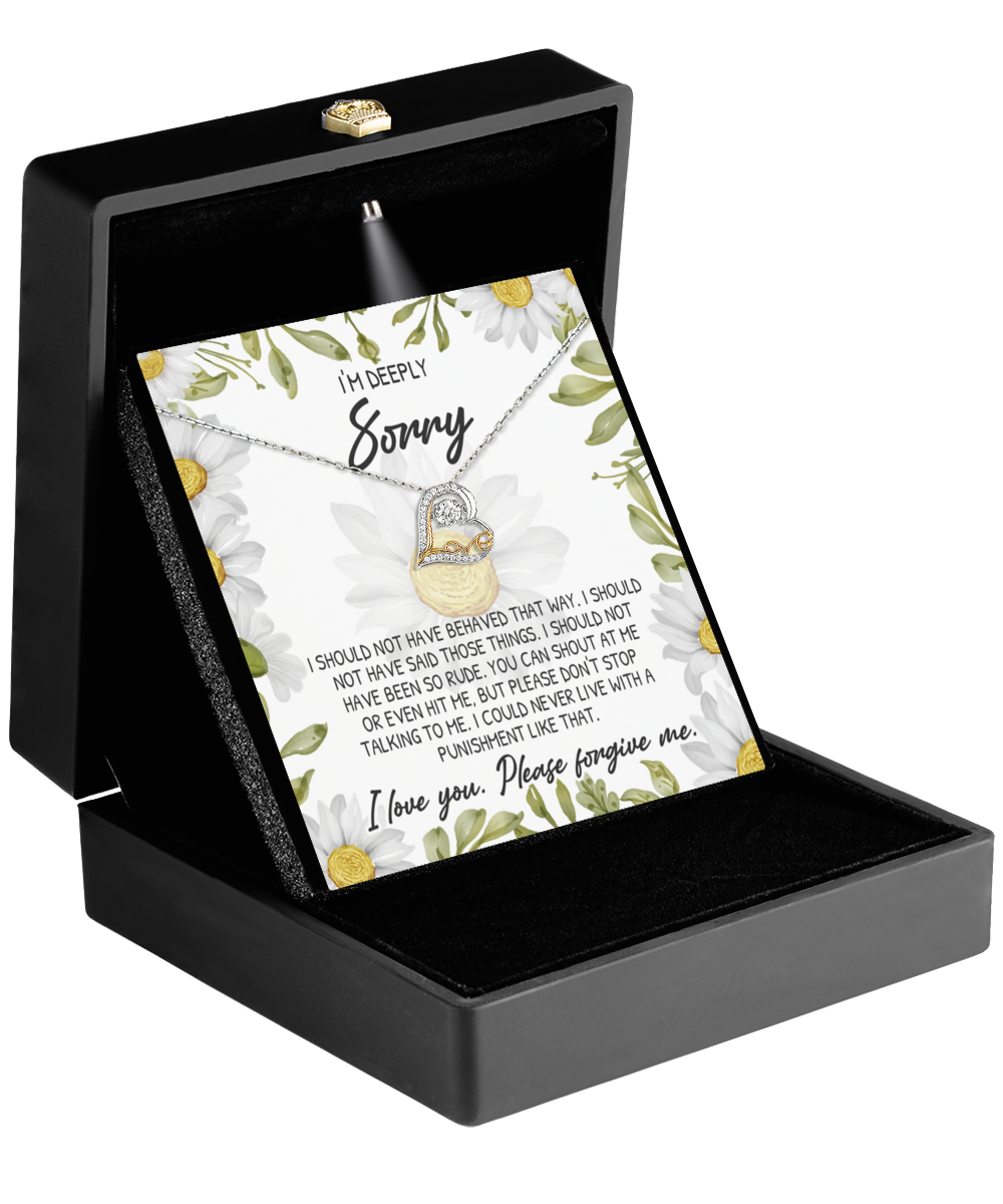 The Sorry-Please Don’t Stop - Love Dancing Necklace, featuring a heart-shaped pendant crafted in 14k gold, is elegantly displayed in an open black box. Completing the presentation is a card adorned with floral designs that conveys an apology message.