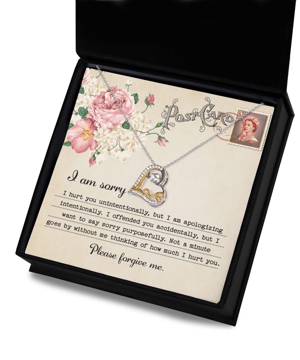 The Sorry-Apologizing Intentionally - Love Dancing Necklace features a 14k gold chain in a box, accompanied by a card that reads, "I am sorry. Please forgive me," adorned with decorative flowers and a vintage stamp depicting a woman's portrait.