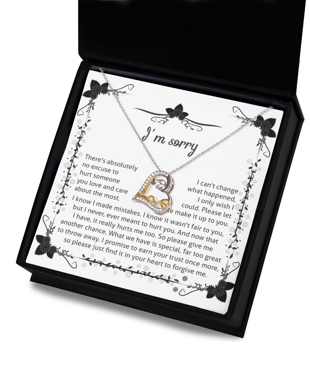 A black jewelry box holds the Sorry-No Excuse - Love Dancing Necklace, made of .925 Sterling Silver with a heart pendant. The inside lid features a heartfelt apology message on white paper, adorned with floral designs. The message conveys regret, a longing to alter the past, a plea for forgiveness, and a pledge to rebuild trust.