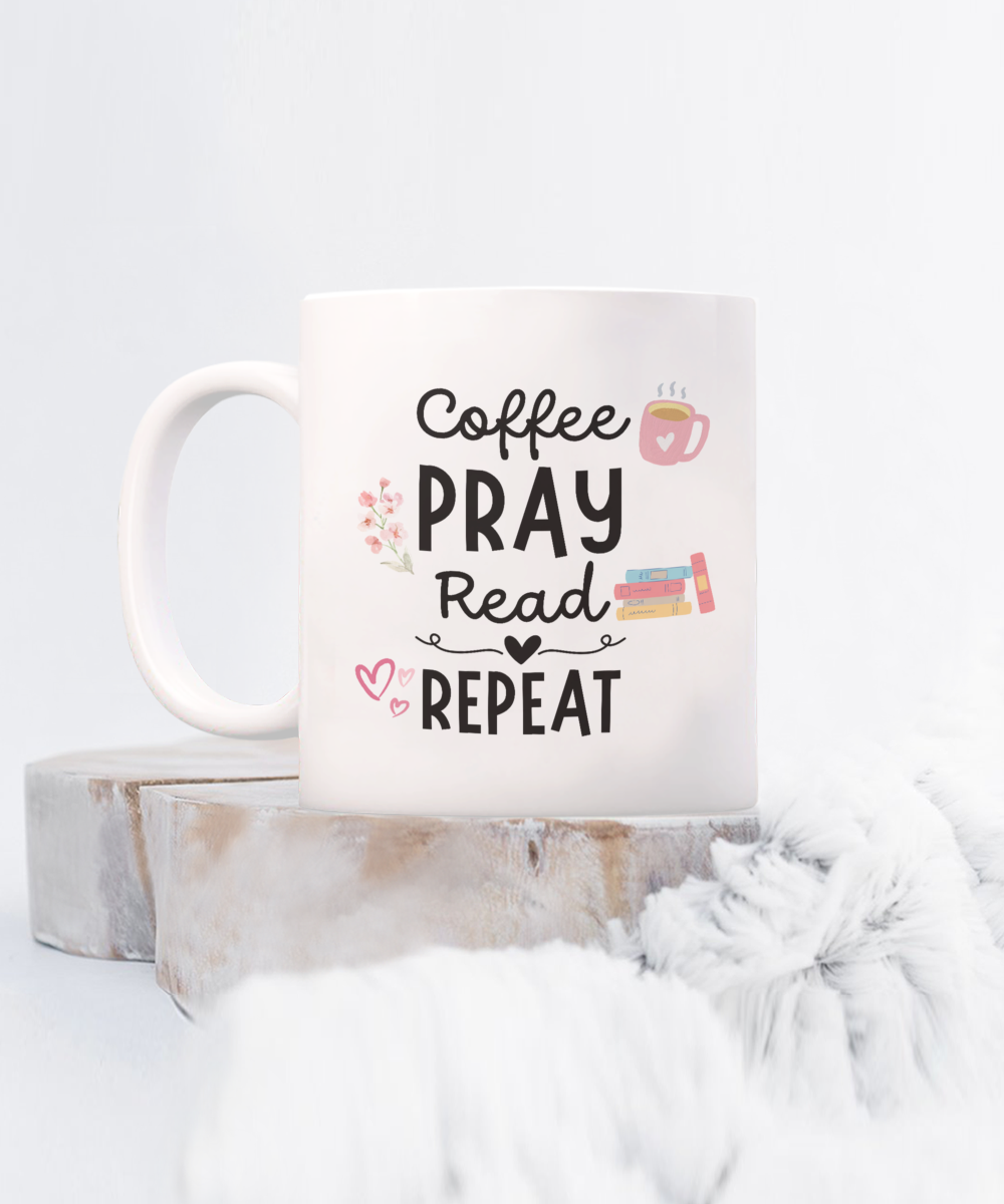 The Coffee Pray Read Repeat Mug, featuring text with hearts, flowers, and books on a wooden surface, is printed and shipped from the USA. Not in stores—get this limited-time offer now!.