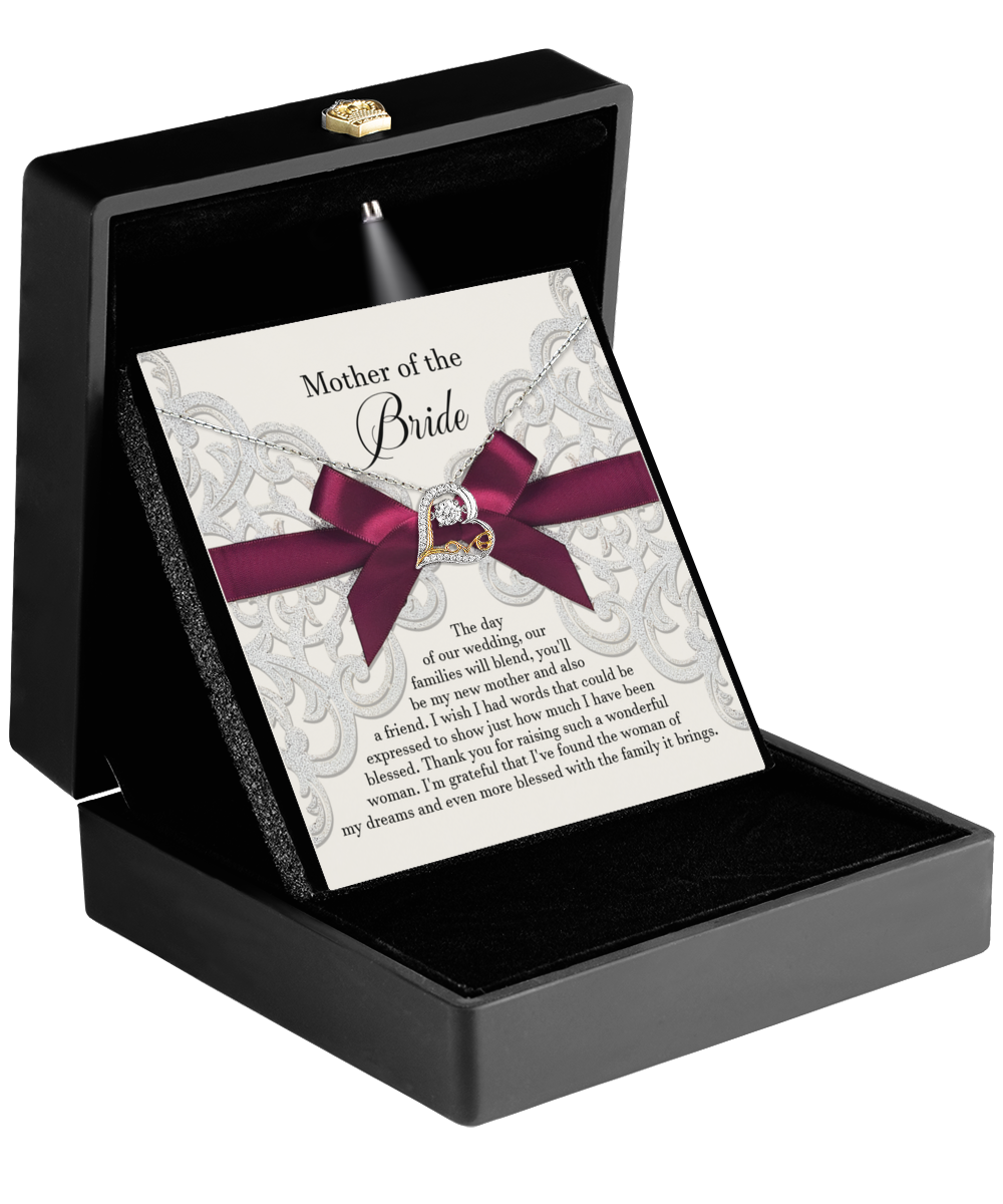 In an open black box, a card labeled "To Bride's Mom, My New Mother - Love Dancing Necklace" embodies maternal love. Enhanced with a red ribbon featuring a small ring, the elegant text beautifully encapsulates the essence of this heartfelt moment.