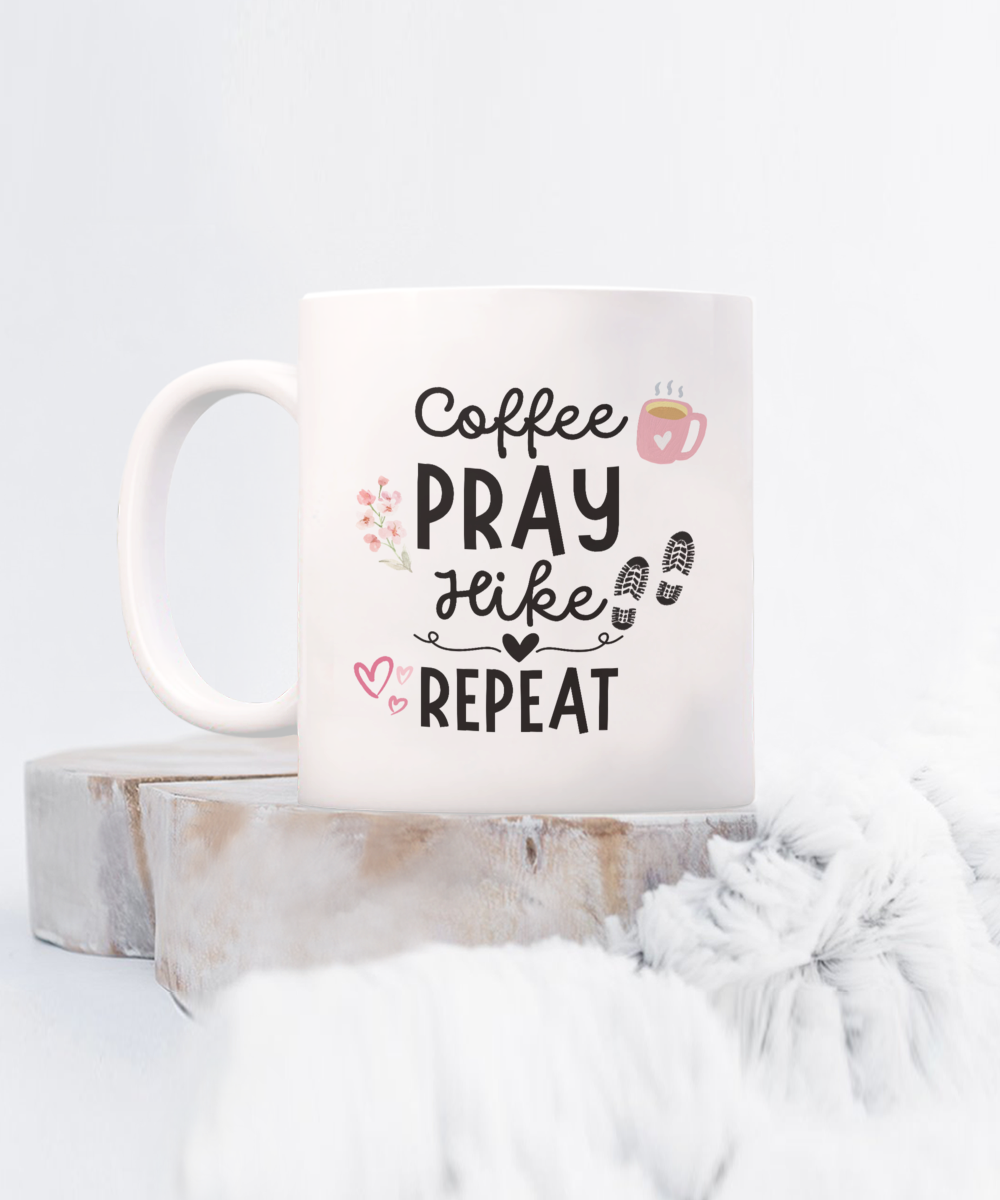 The "Coffee Pray Hike Repeat" Coffee Mug features a coffee cup, flowers, and hiking boots illustration. It's printed and shipped from the USA and displayed on wooden blocks with a fluffy white background. Available for a limited time only, it's the perfect appreciation gift for hikers.