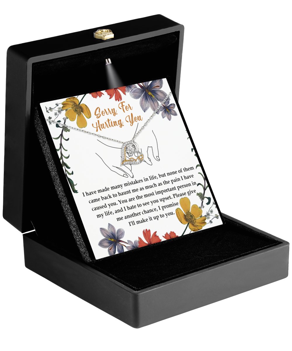 In an open black jewelry box, the Sorry-Haunt Me - Love Dancing Necklace rests on a floral card with an apology message, featuring a heart-shaped pendant. It's a heartfelt gift for your wife.