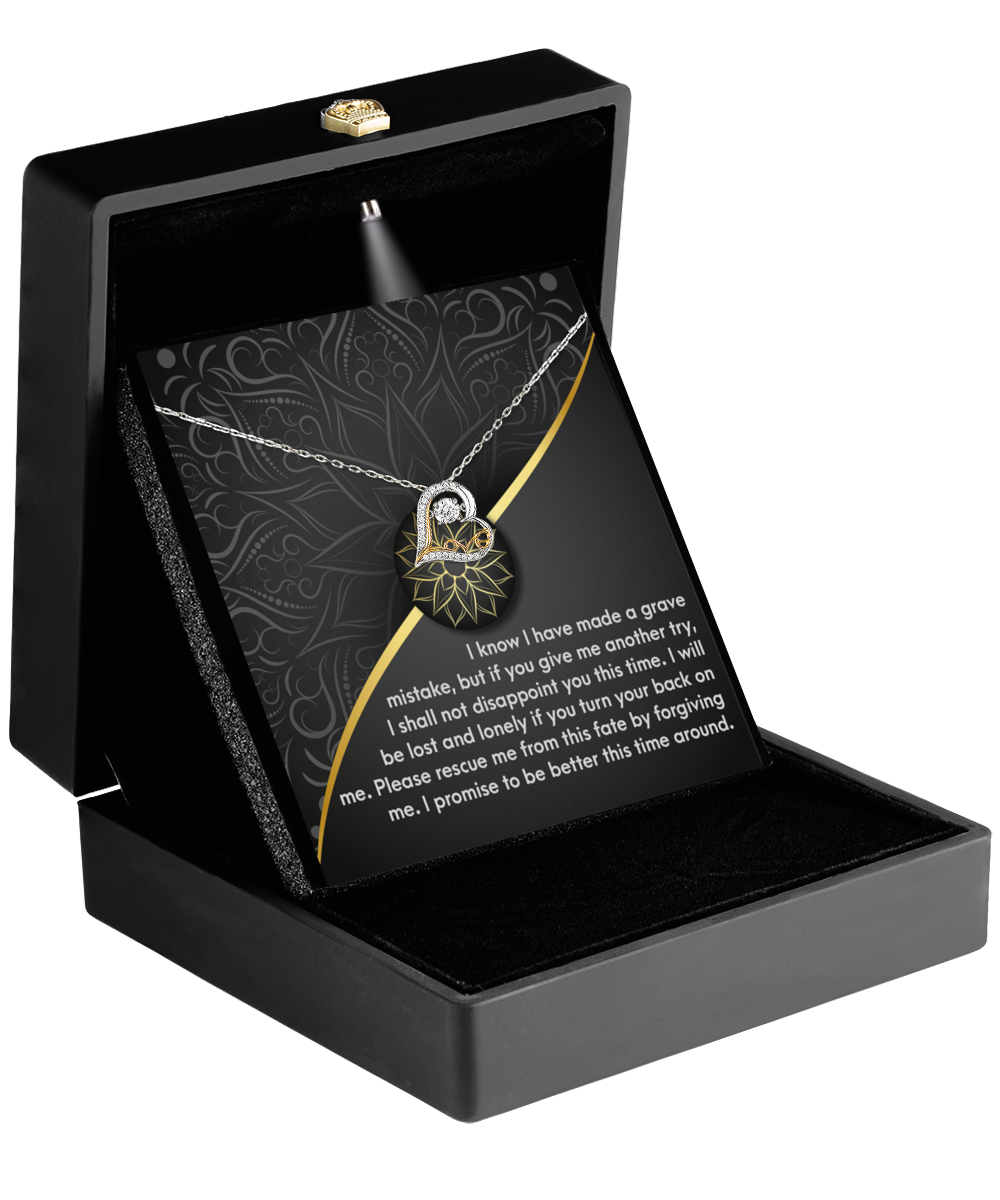 A Sorry-Turn Your Back - Love Dancing necklace with a geometric pendant is displayed in an open black jewelry box with an illuminated interior. A heartfelt message is printed on a card inside the box.