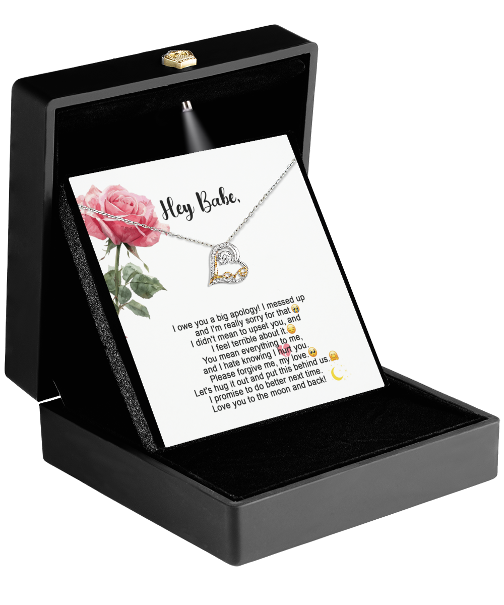 An open black jewelry box showcases the Sorry-Hug It Out - Love Dancing Necklace, featuring a heart-shaped pendant, gracefully positioned on a card embellished with a rose illustration and an inscribed message. Crafted from 14k gold, it embodies timeless elegance and heartfelt sentiment.