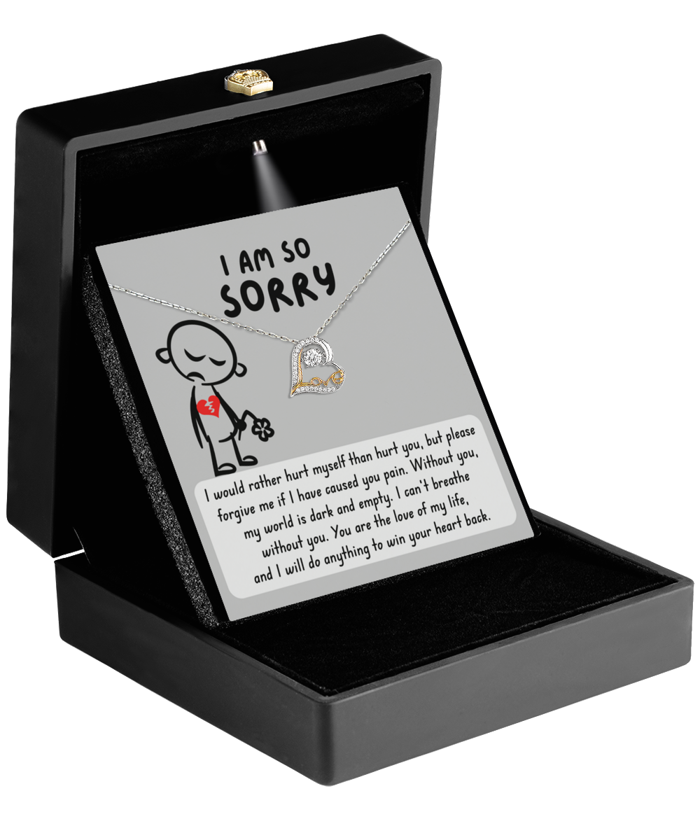 A black jewelry box containing a Sorry-Dark And Empty – Love Dancing Necklace in Sterling Silver and an apology card that says, "I am so sorry." Along with a drawing of a person holding a heart, the message expresses regret and a wish for forgiveness.