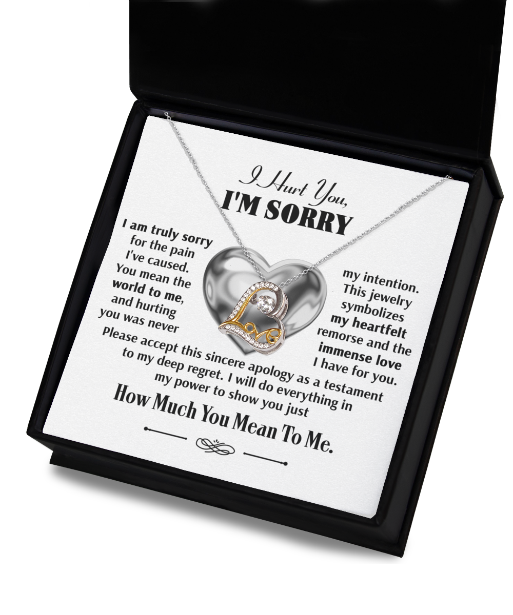 The Sorry-Sincere Apology - Love Dancing Necklace, showcasing a sterling silver heart and a 14k gold letter "L," is beautifully presented in an open black box, complete with a heartfelt apology note inside.